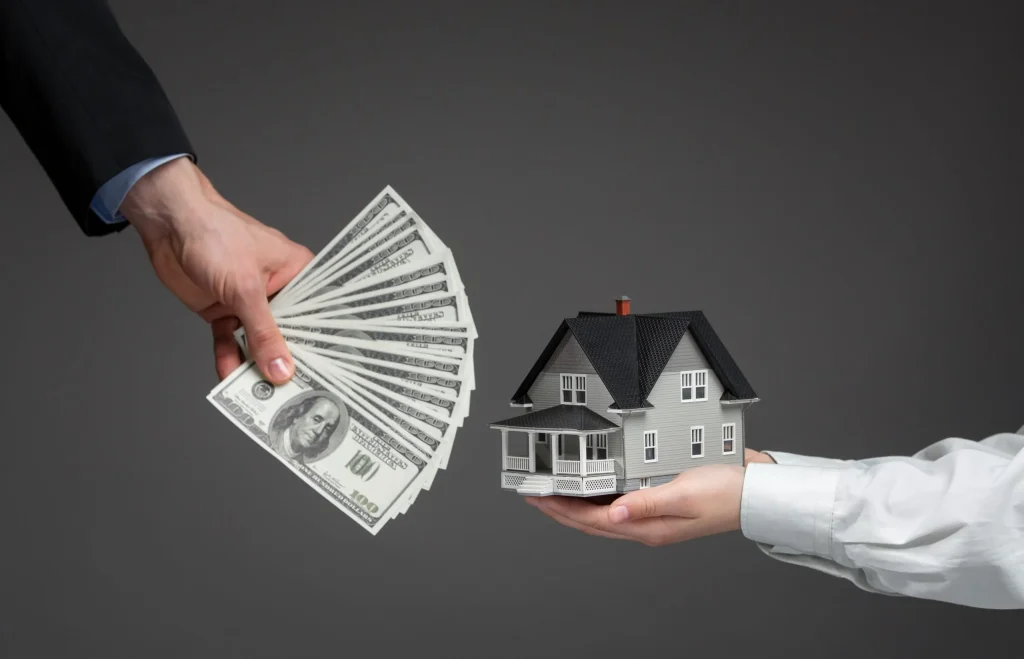 A hand holding cash on one side and a hand holding a house on the other, representing the financial relief of selling a home for cash in Raleigh.