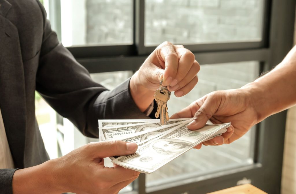 A person handing over house keys while receiving cash from another person in Raleigh, NC.