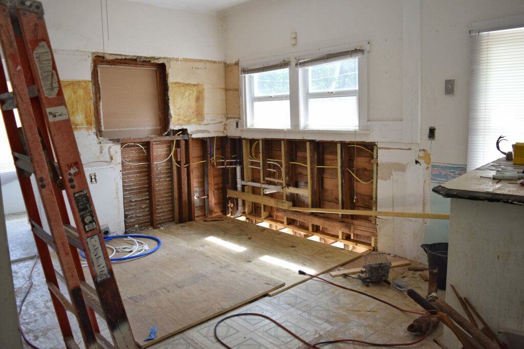 A damaged house interior with cracked walls, peeling paint, and broken flooring, symbolizing the need for major repairs.